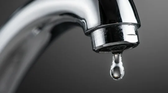 Gros plan sur un robinet chromé avec goutte d'eau suspendue